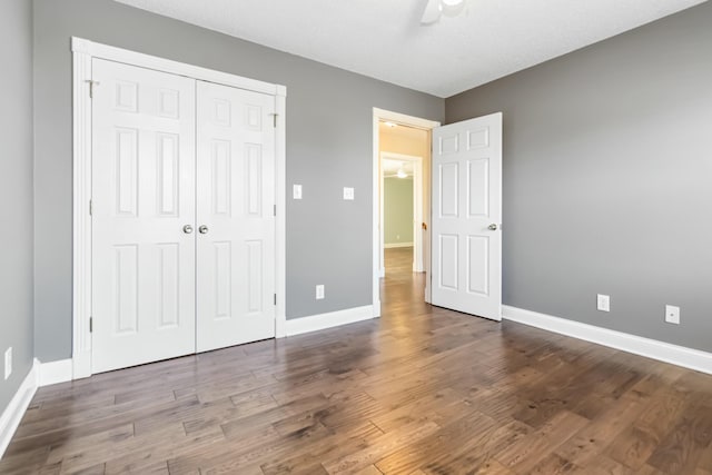 unfurnished bedroom with ceiling fan, a closet, wood finished floors, and baseboards