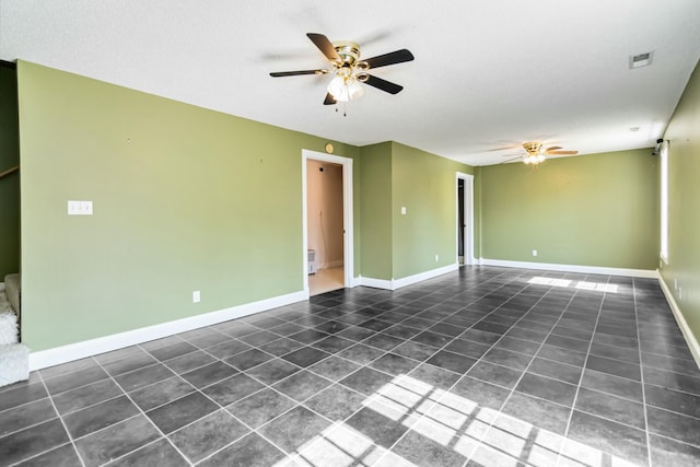 empty room with ceiling fan, tile patterned flooring, visible vents, and baseboards