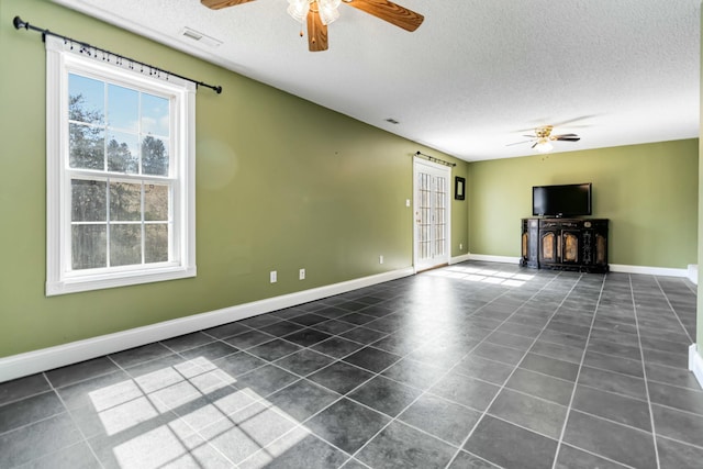 unfurnished living room featuring a ceiling fan, visible vents, a textured ceiling, and baseboards