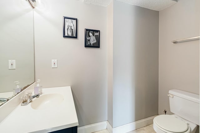 half bath with baseboards, a textured ceiling, toilet, and vanity