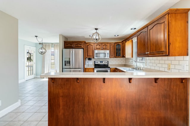 kitchen featuring light tile patterned flooring, stainless steel appliances, a sink, light countertops, and backsplash