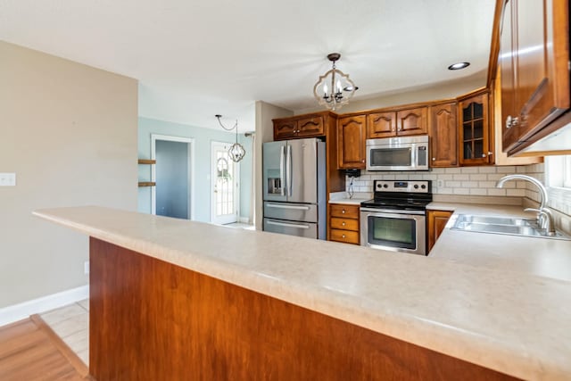 kitchen featuring a notable chandelier, a sink, light countertops, appliances with stainless steel finishes, and decorative backsplash