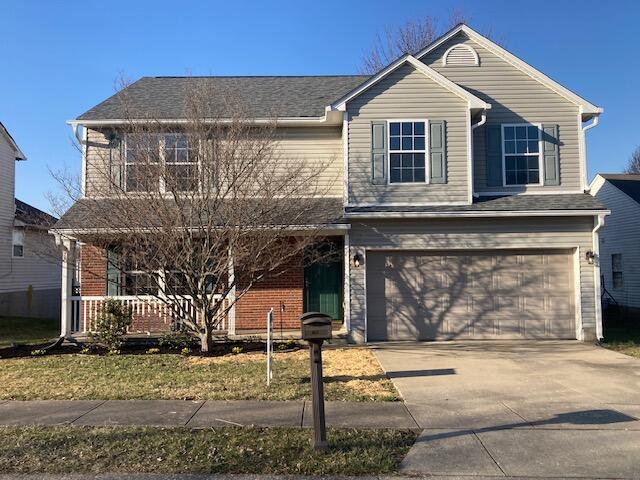 traditional home with brick siding, covered porch, concrete driveway, and a garage