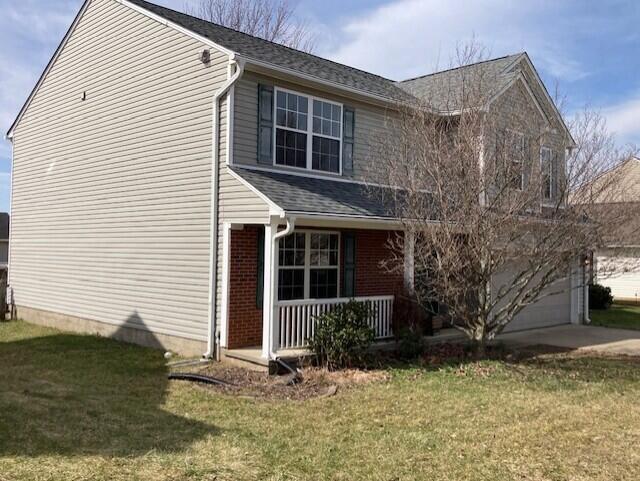 view of front facade featuring an attached garage, a porch, concrete driveway, and a front lawn