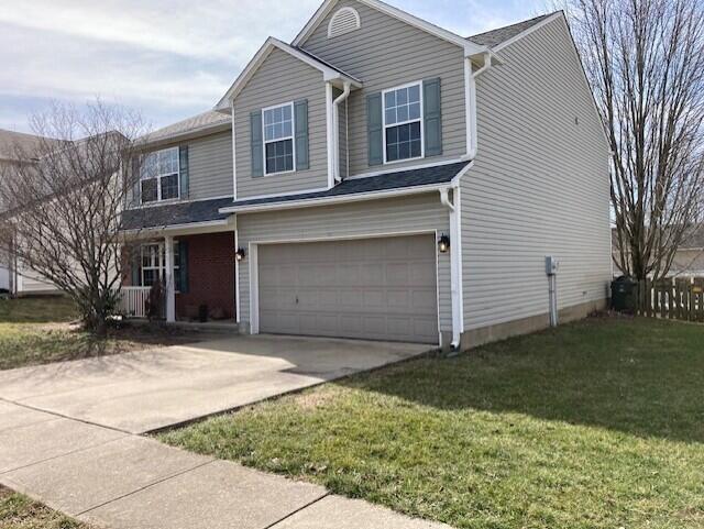 traditional-style house with a front lawn, an attached garage, and driveway