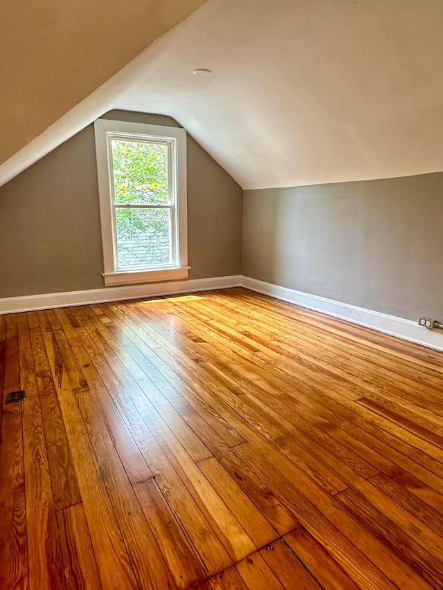 additional living space featuring lofted ceiling, wood-type flooring, and baseboards