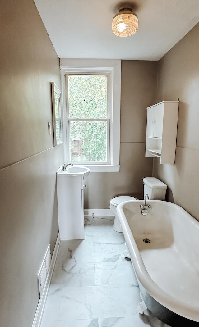 full bathroom featuring baseboards, visible vents, toilet, marble finish floor, and a freestanding bath