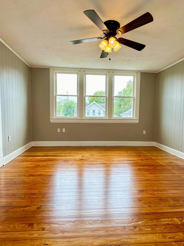 empty room featuring plenty of natural light, a textured ceiling, baseboards, and wood finished floors