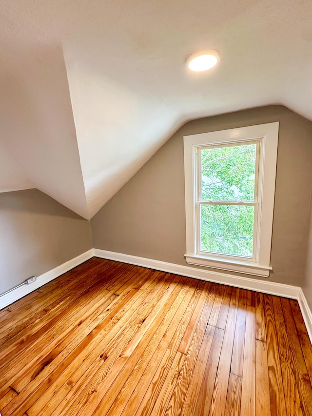 bonus room featuring lofted ceiling, hardwood / wood-style flooring, and baseboards