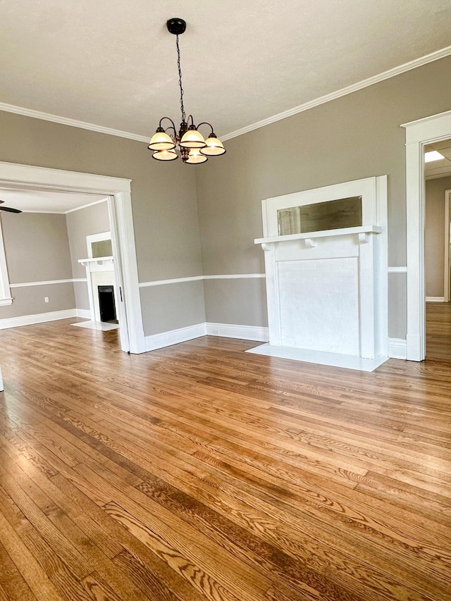 interior space with an inviting chandelier, a fireplace with flush hearth, ornamental molding, and wood finished floors