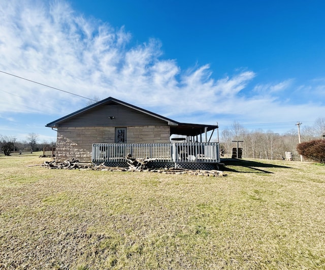 exterior space with stone siding, a lawn, and a wooden deck