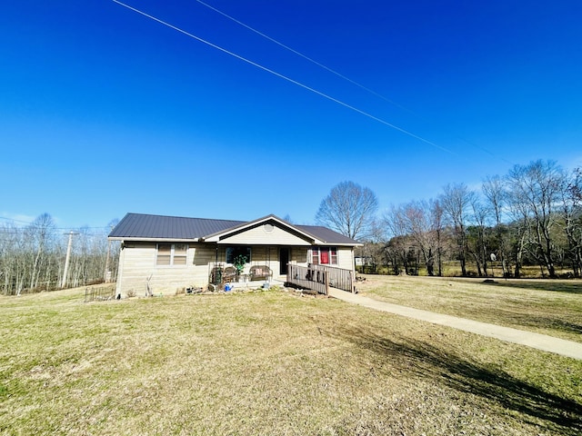 view of front of home with covered porch, metal roof, and a front lawn