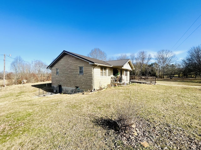 view of side of home with stone siding, metal roof, and a yard