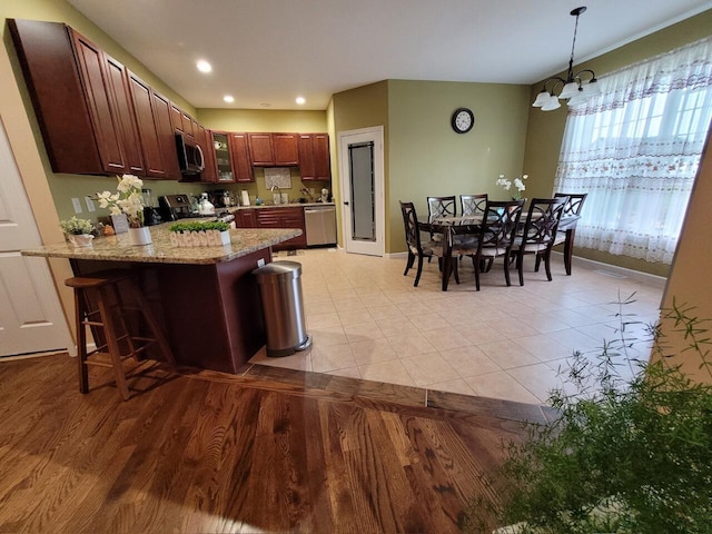 kitchen featuring decorative light fixtures, a kitchen breakfast bar, a peninsula, an inviting chandelier, and stainless steel appliances