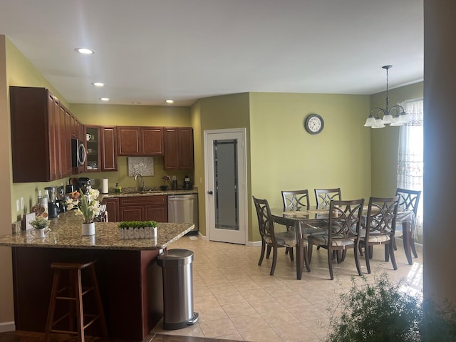 kitchen featuring glass insert cabinets, appliances with stainless steel finishes, a peninsula, stone countertops, and a sink