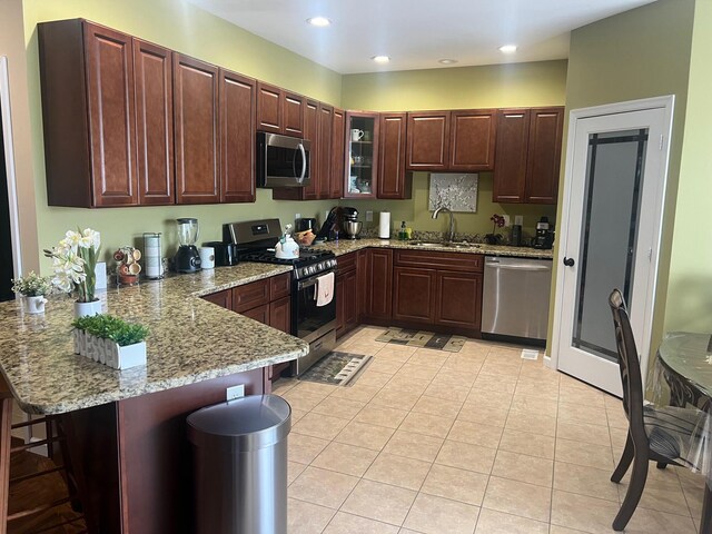 kitchen featuring a peninsula, recessed lighting, a sink, stainless steel appliances, and a kitchen breakfast bar