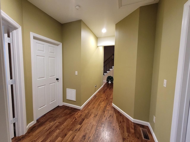 hallway with stairs, dark wood-type flooring, baseboards, and visible vents