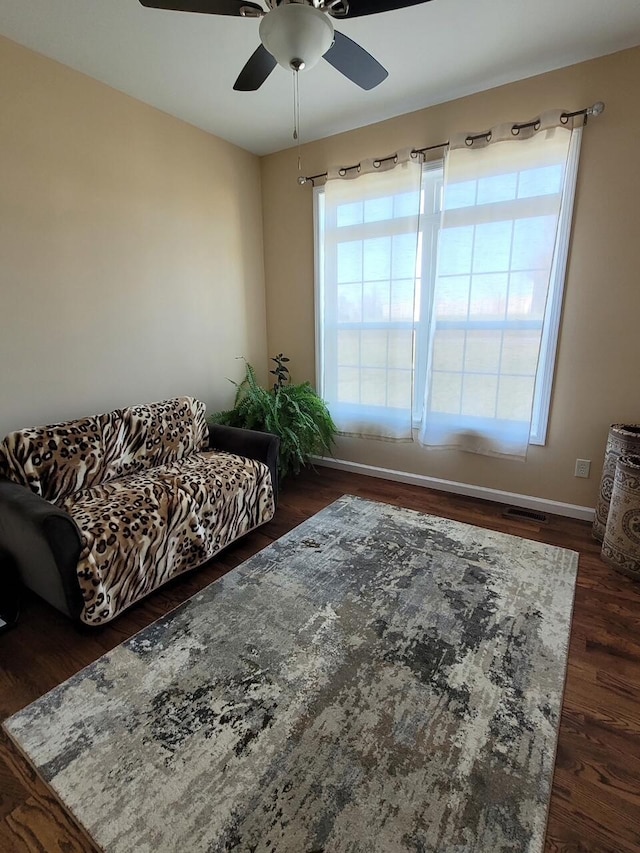 living room featuring a ceiling fan, visible vents, dark wood-style flooring, and a wealth of natural light