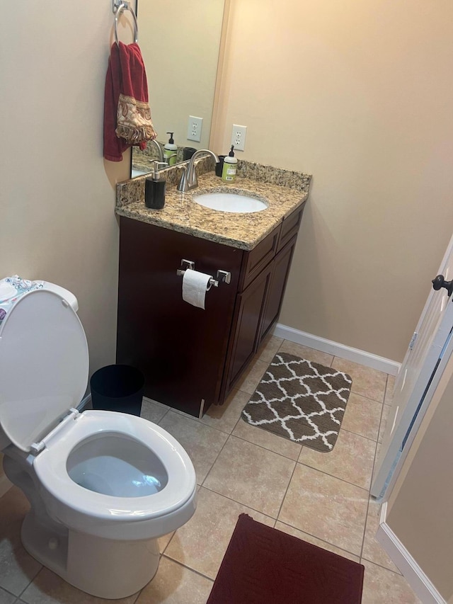 half bathroom featuring vanity, toilet, baseboards, and tile patterned flooring