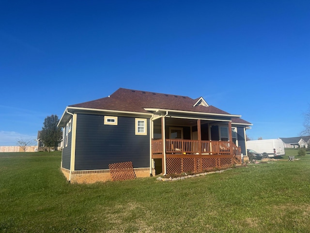 rear view of property with a yard, roof with shingles, and a wooden deck