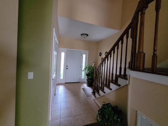 foyer entrance with light tile patterned floors and stairs