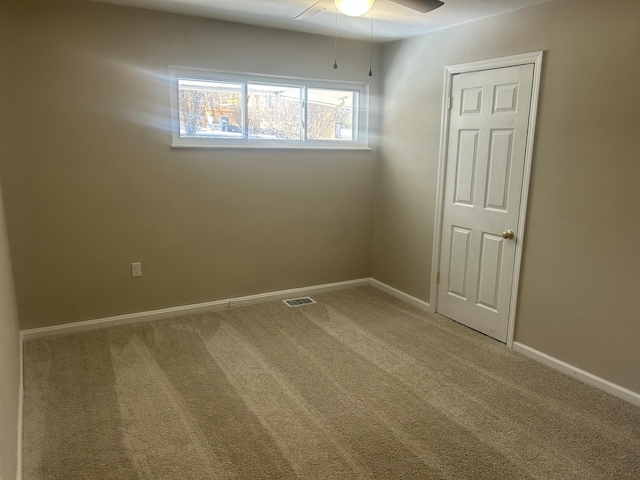 carpeted empty room with ceiling fan, visible vents, and baseboards