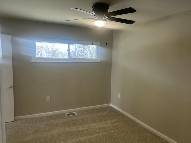 carpeted spare room with baseboards, visible vents, and a ceiling fan