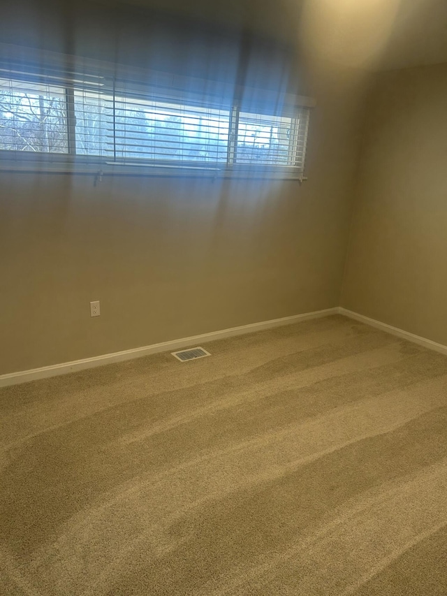 unfurnished room with baseboards, visible vents, and carpet flooring