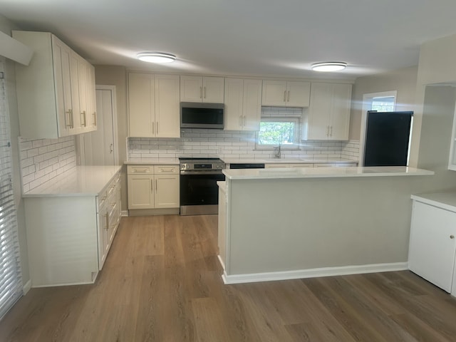 kitchen with appliances with stainless steel finishes, light countertops, light wood-style floors, white cabinetry, and a sink