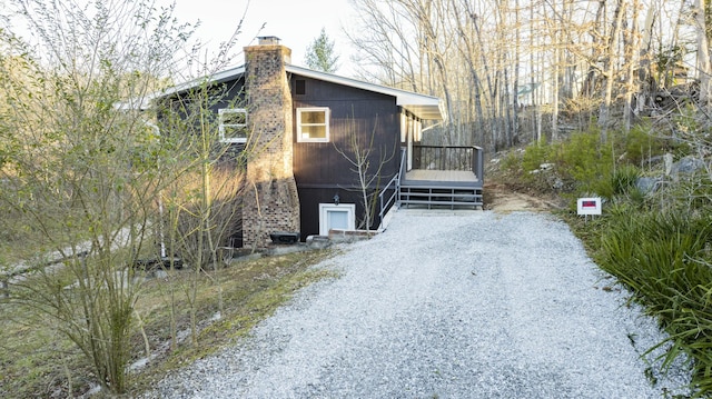 view of property exterior featuring driveway and a chimney