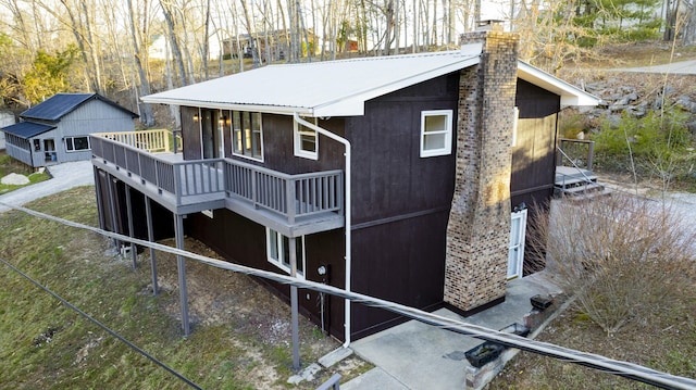 view of home's exterior with a chimney, metal roof, and a deck