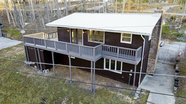 back of property featuring a wooden deck, a chimney, and metal roof