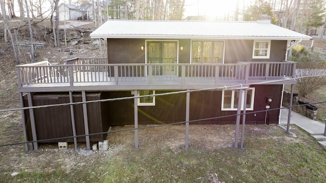 back of property with a chimney, a wooden deck, and metal roof