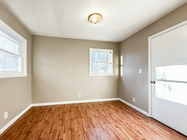 unfurnished room featuring baseboards and light wood-style floors