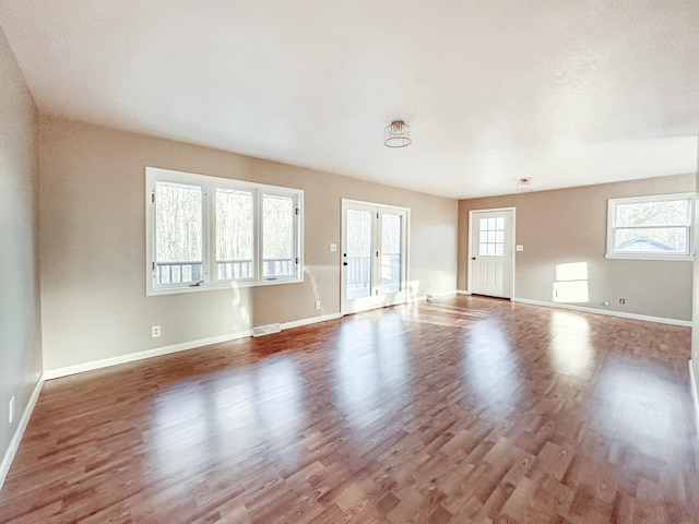 unfurnished living room with visible vents, baseboards, and wood finished floors