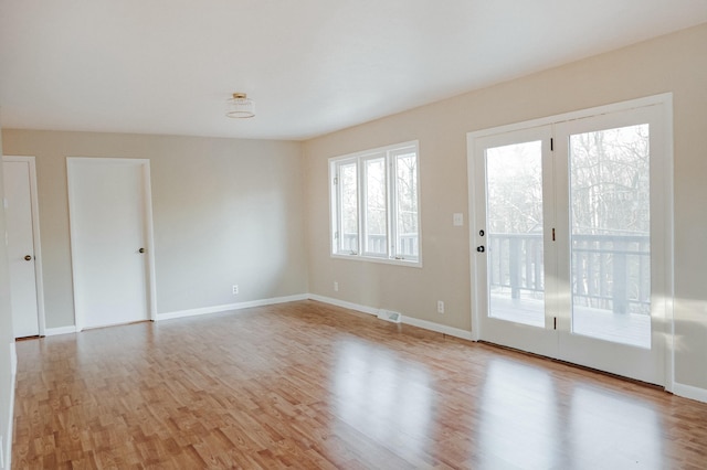 unfurnished room with visible vents, wood finished floors, and baseboards