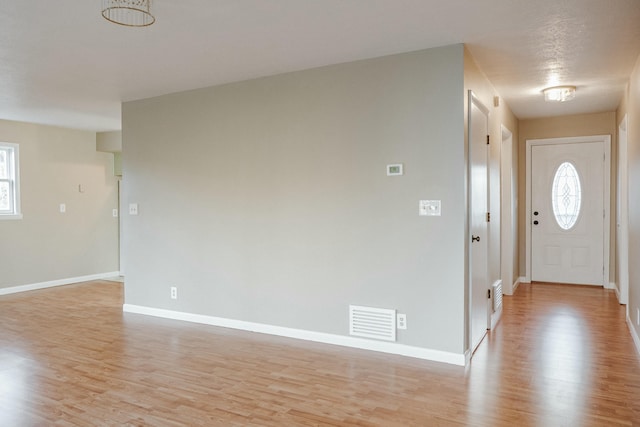 foyer entrance featuring light wood finished floors, visible vents, plenty of natural light, and baseboards