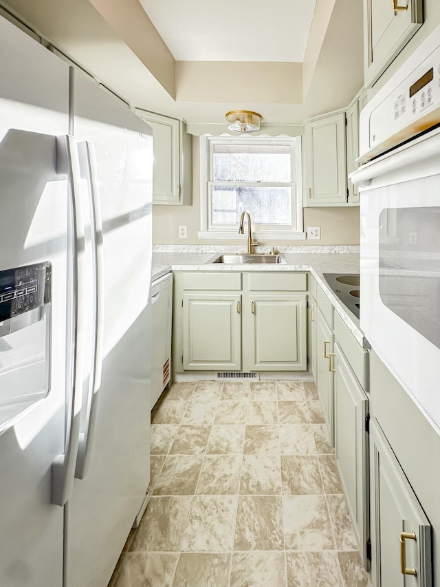 kitchen featuring a sink, visible vents, white appliances, and light countertops