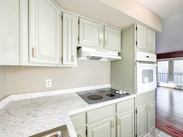 kitchen featuring under cabinet range hood, white cabinetry, light countertops, white oven, and black electric cooktop