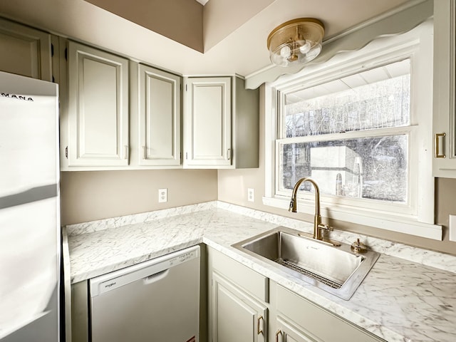 kitchen with a sink, dishwasher, light countertops, and freestanding refrigerator