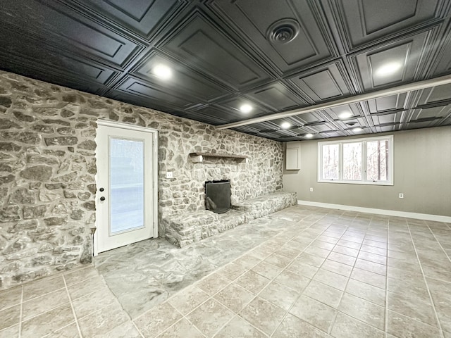 below grade area featuring light tile patterned flooring, visible vents, baseboards, and an ornate ceiling