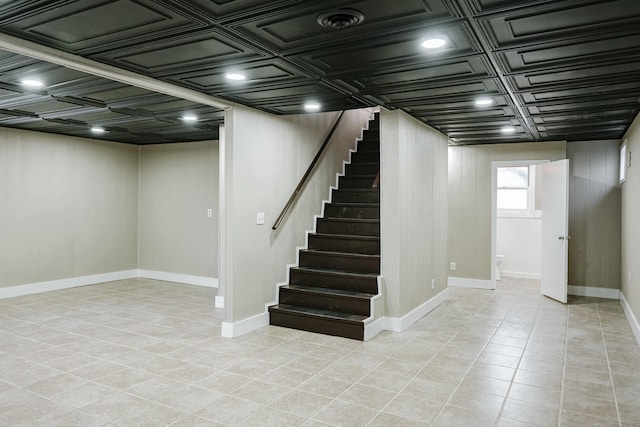 below grade area with light tile patterned flooring, stairs, and baseboards