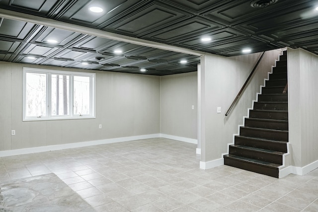 basement featuring stairway, baseboards, and an ornate ceiling