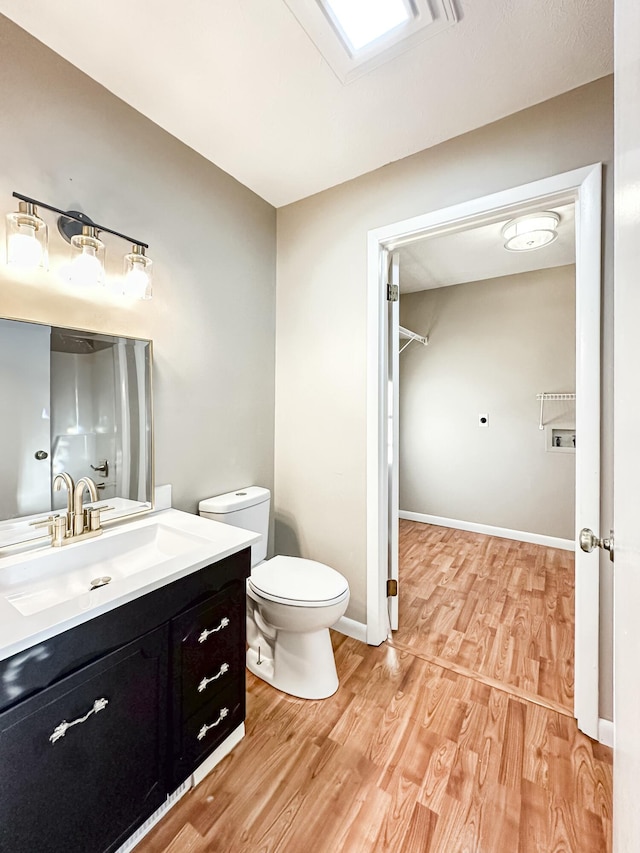 bathroom featuring toilet, vanity, baseboards, and wood finished floors