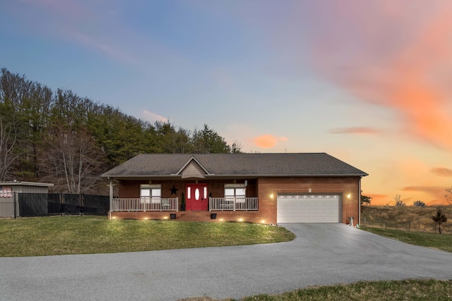 ranch-style house featuring brick siding, a porch, an attached garage, a front yard, and driveway