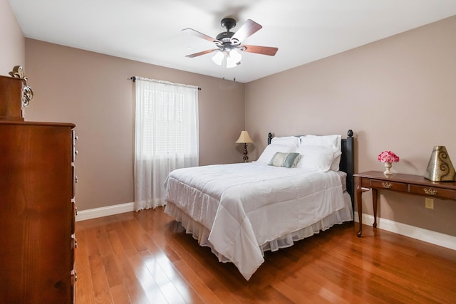 bedroom featuring a ceiling fan, baseboards, and wood finished floors