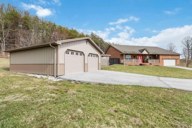 ranch-style home with a porch, a front lawn, a detached garage, and an outdoor structure