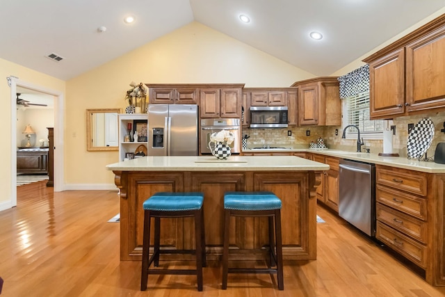 kitchen with visible vents, a kitchen island, appliances with stainless steel finishes, light countertops, and a sink