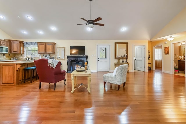 living area with lofted ceiling, ceiling fan, light wood-type flooring, and recessed lighting