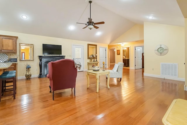 living area with high vaulted ceiling, visible vents, baseboards, a ceiling fan, and light wood-type flooring